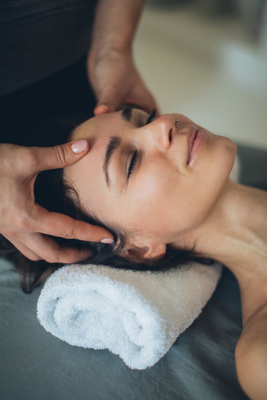 a woman lying down while having her head massage by a person